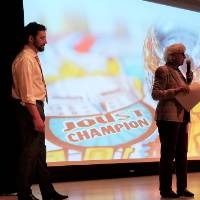 A man stand on stage next to a woman with a microphone
